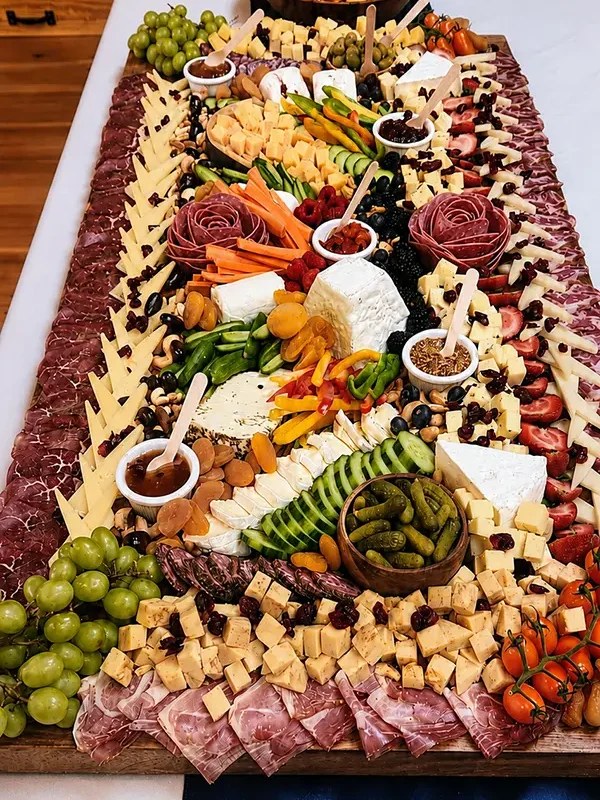 Photo of a charcuterie board of meats, cheeses, pickles, and fruit.